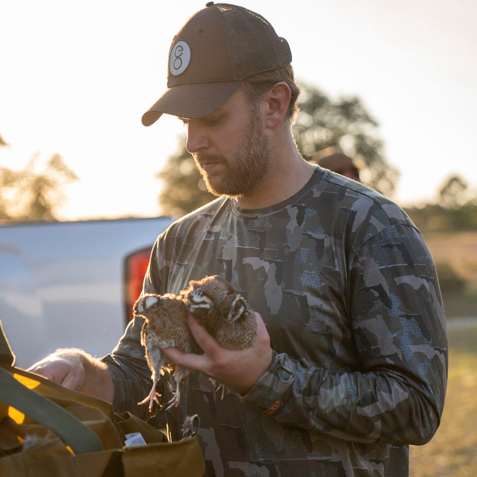 Man holding two quail wearing Florida State Camo long sleeve shirt