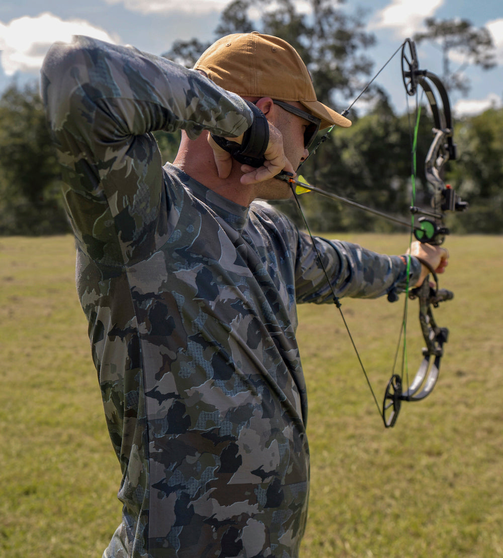 Man shooting bow wearing Michigan State Camo long sleeve shirt