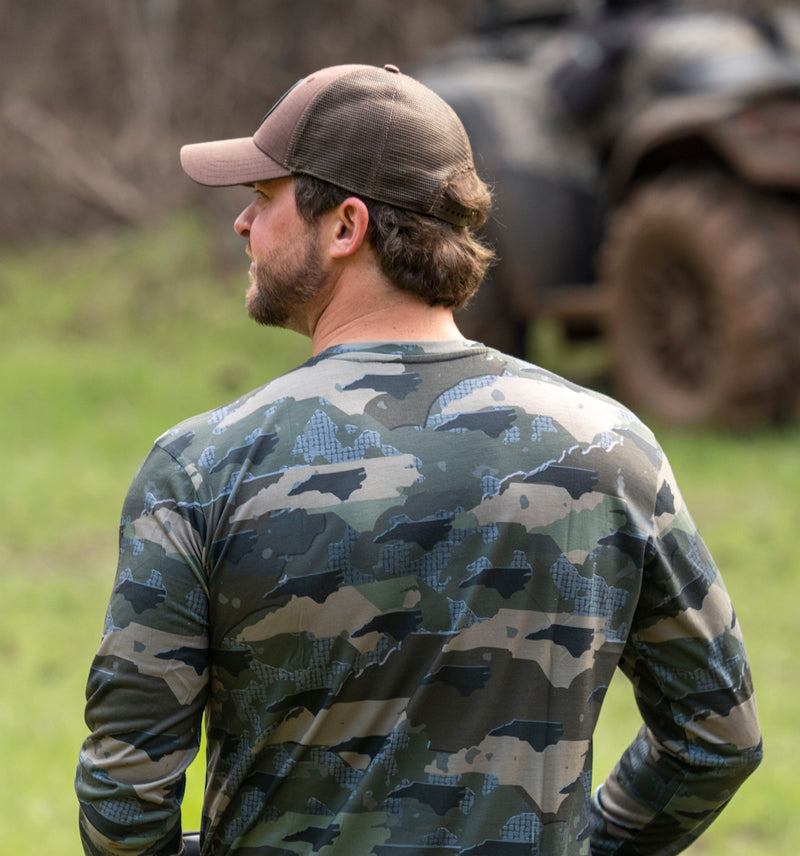 Man working in field wearing North Carolina State Camo long sleeve shirt