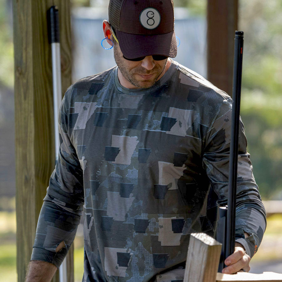 Man holding benelli shotgun wearing Arkansas State Camo long sleeve shirt